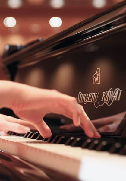 Tay nghệ sĩ chơi đàn Shigeru Kawai, cận cảnh logo trên thân đàn