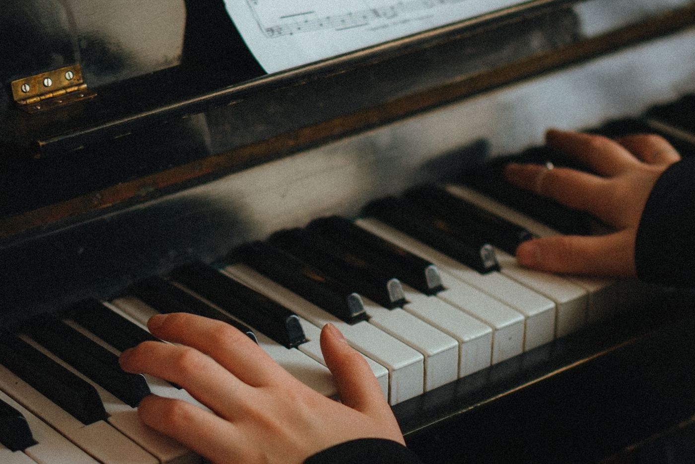 Đôi tay chơi đàn piano cơ với bản nhạc