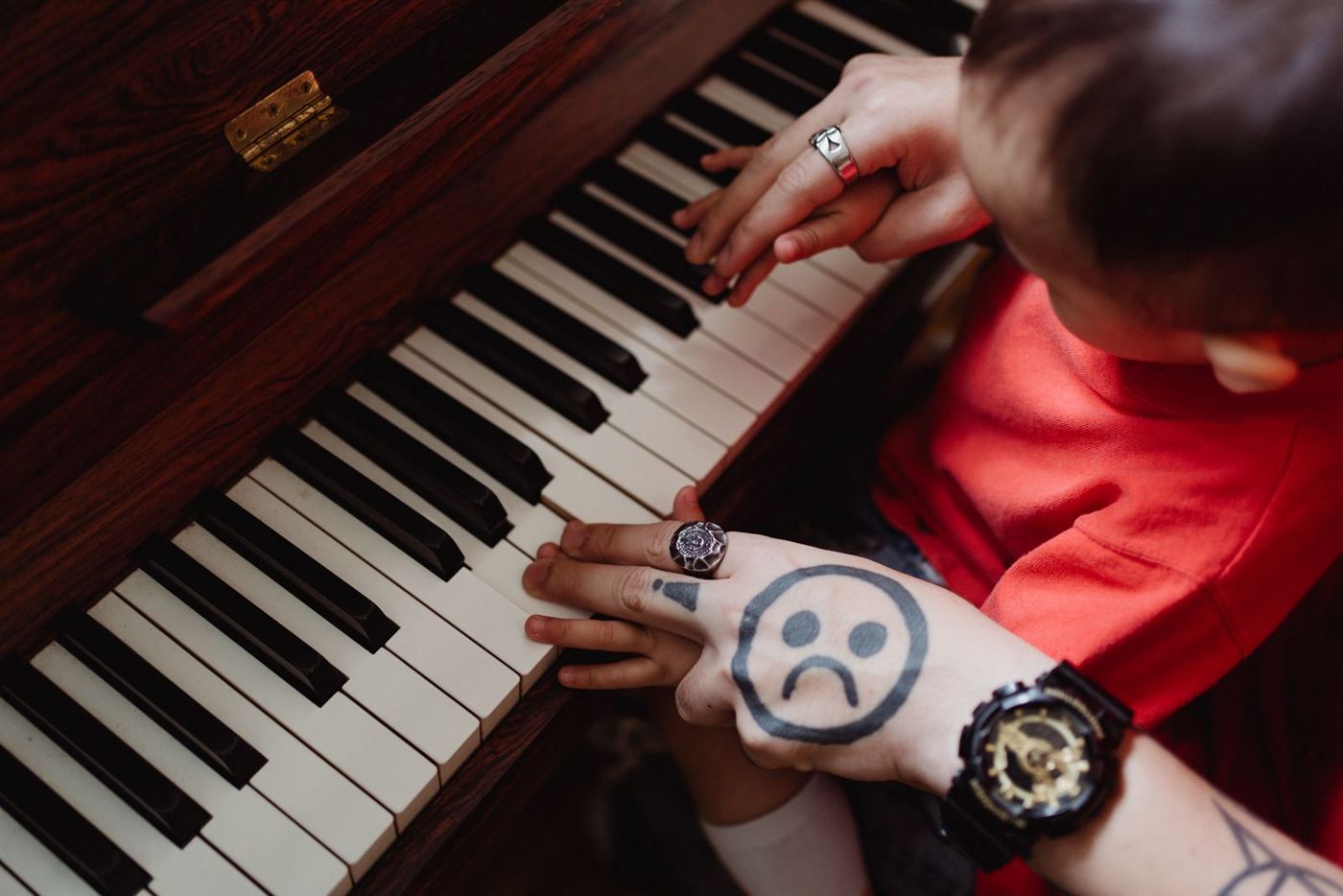 Bàn tay vẽ mặt buồn đặt trên phím đàn piano — khi việc học đàn bắt đầu thấy chán