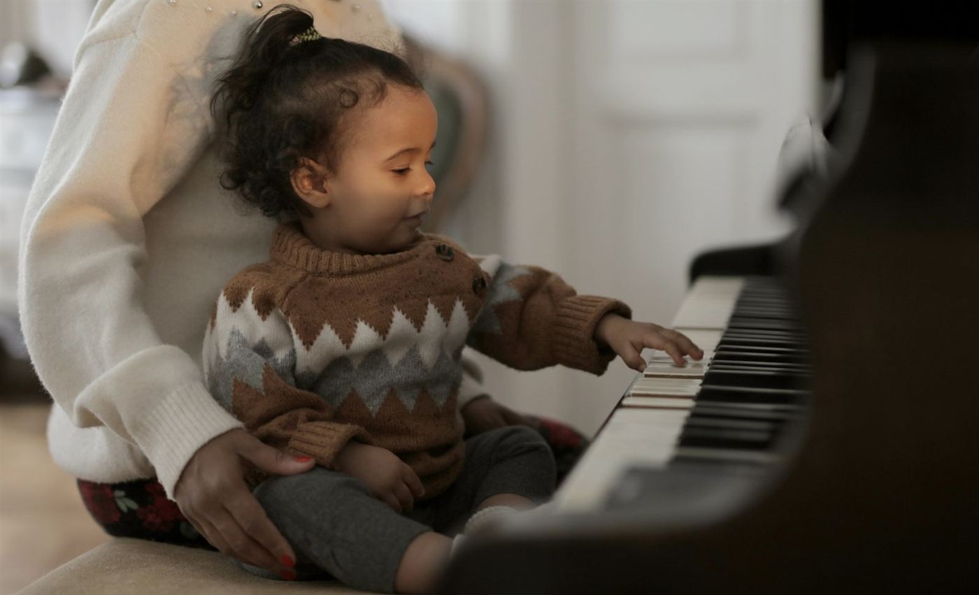 Bé nhỏ ngồi trong lòng mẹ, làm quen với phím đàn piano