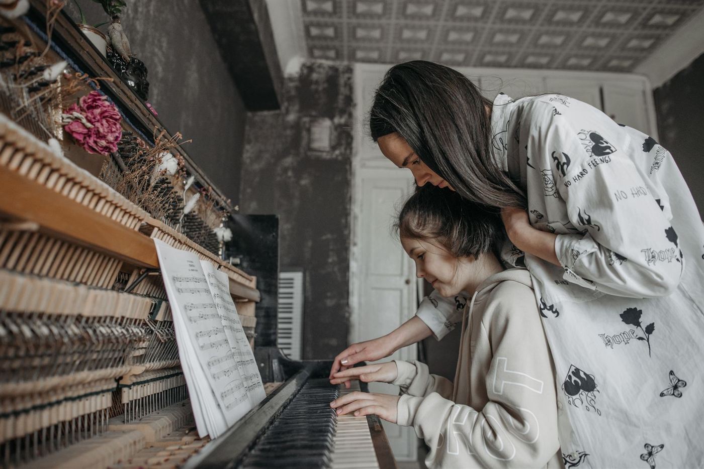 Cô giáo hướng dẫn bé gái tập đàn piano cơ