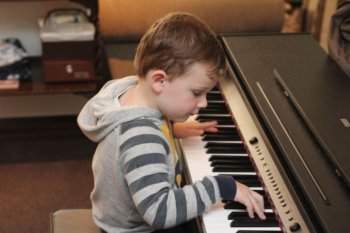 Bé trai tập đàn trên một cây piano điện ở nhà